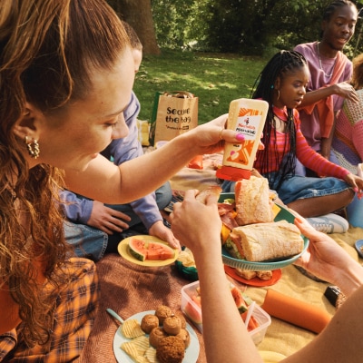 People at a picnic hand squeezing Nando's PERinaise onto a plate